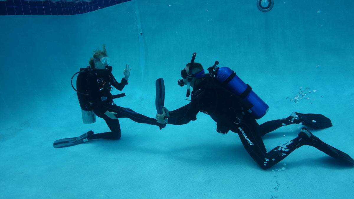 Diver assisting another diver with a leg stretch underwater