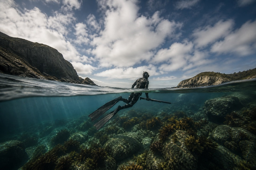 Spearfisher underwater with a speargun and long freediving fins