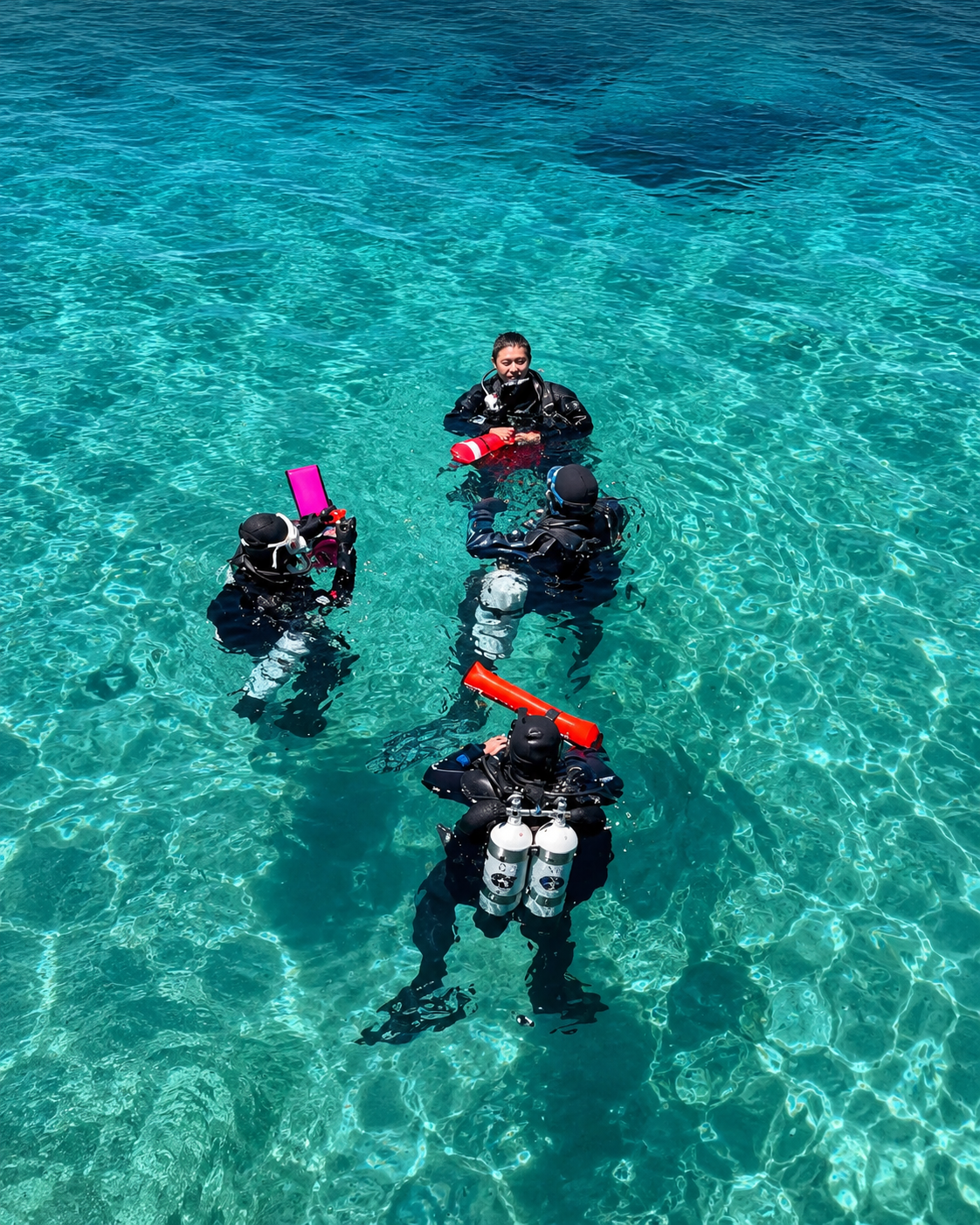 Four technical divers at the surface with doubles and training equipment