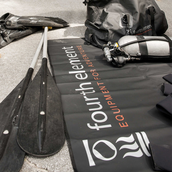 Fourth Element Changing Mat holding dive equipment beside fins and a gear bag