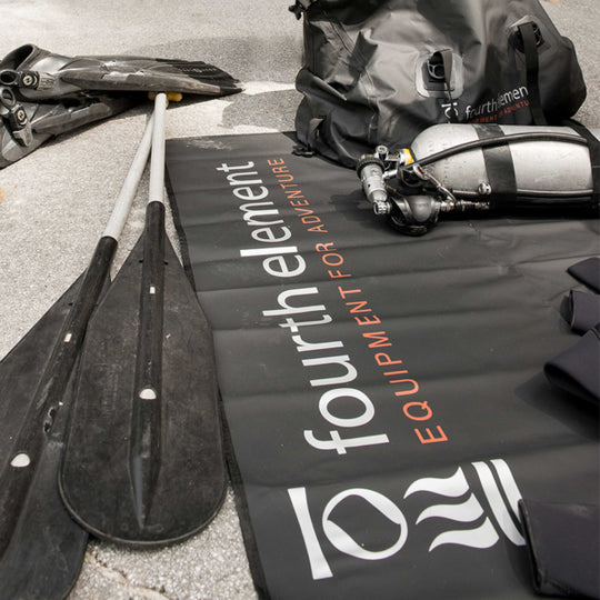Fourth Element Changing Mat holding dive equipment beside fins and a gear bag